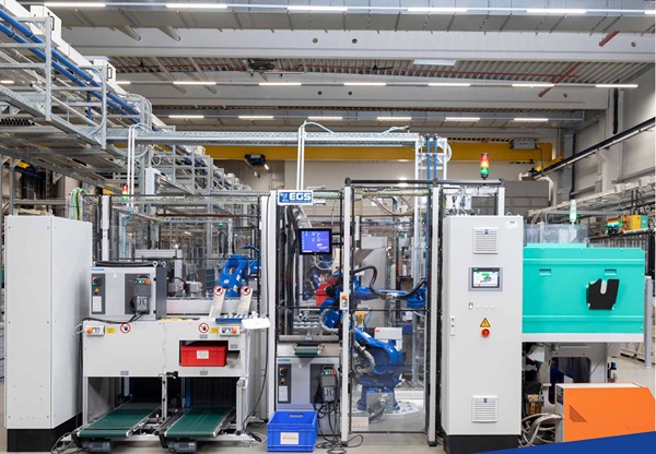 Blauer Yaskawa Roboter in Zelle - Automation von der Herstellung von Kunststoffteilen