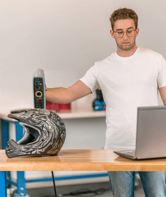 Professional using a handheld HP DesignScan 3D scanner to capture the geometry of a decorated motorcycle helmet